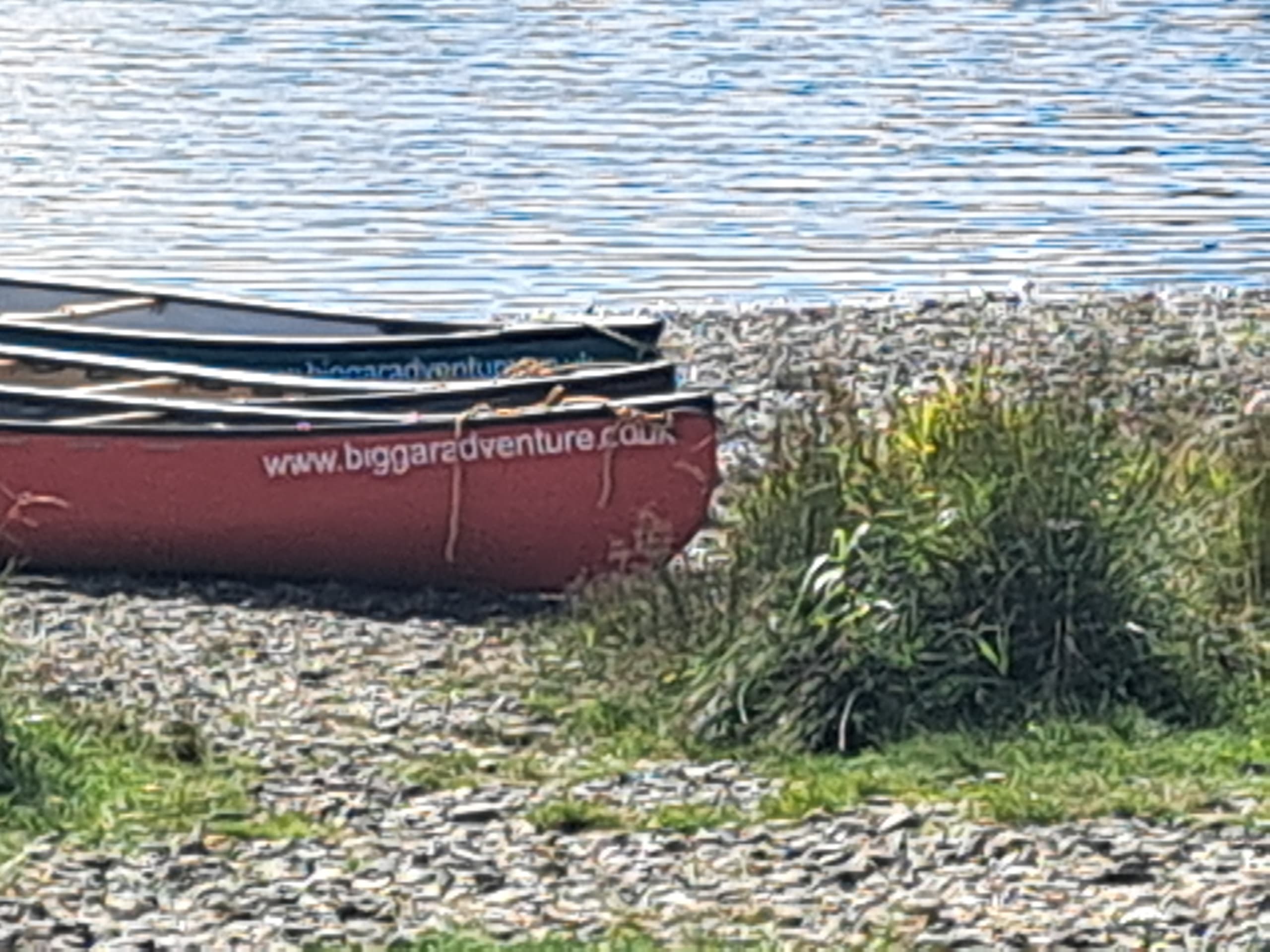 Red canoe resting on a pebbled shore of a highland lake, calm