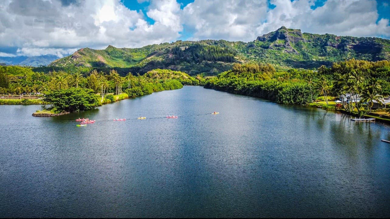 Calm lake with mountains and kayaks in tropical valley aerial