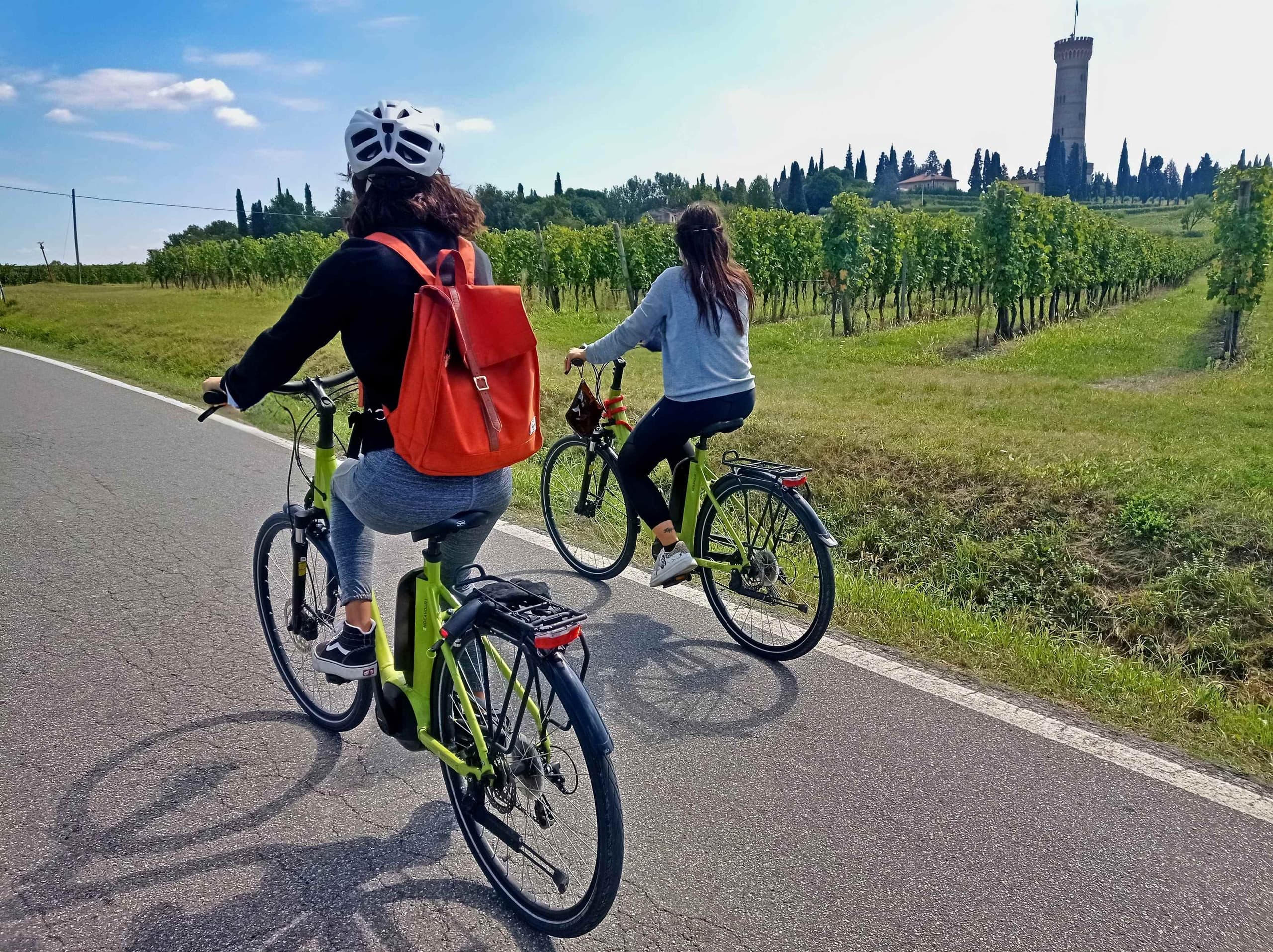 Two cyclists riding country road near Italian countryside vista