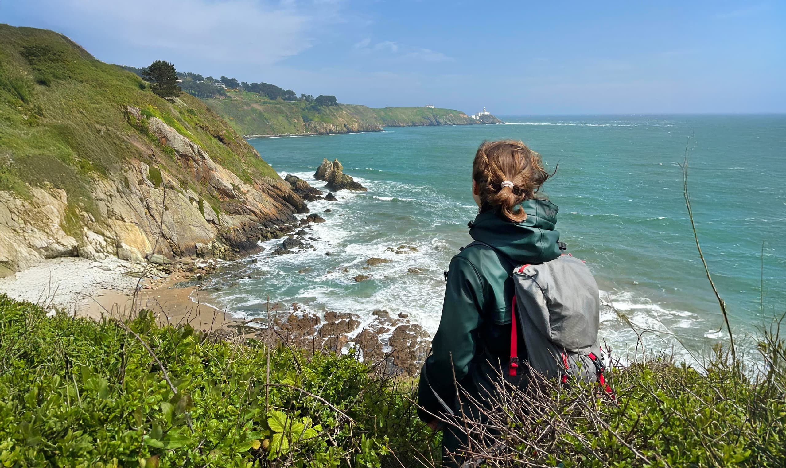 Solo hiker with backpack viewing rugged coastline from cliff