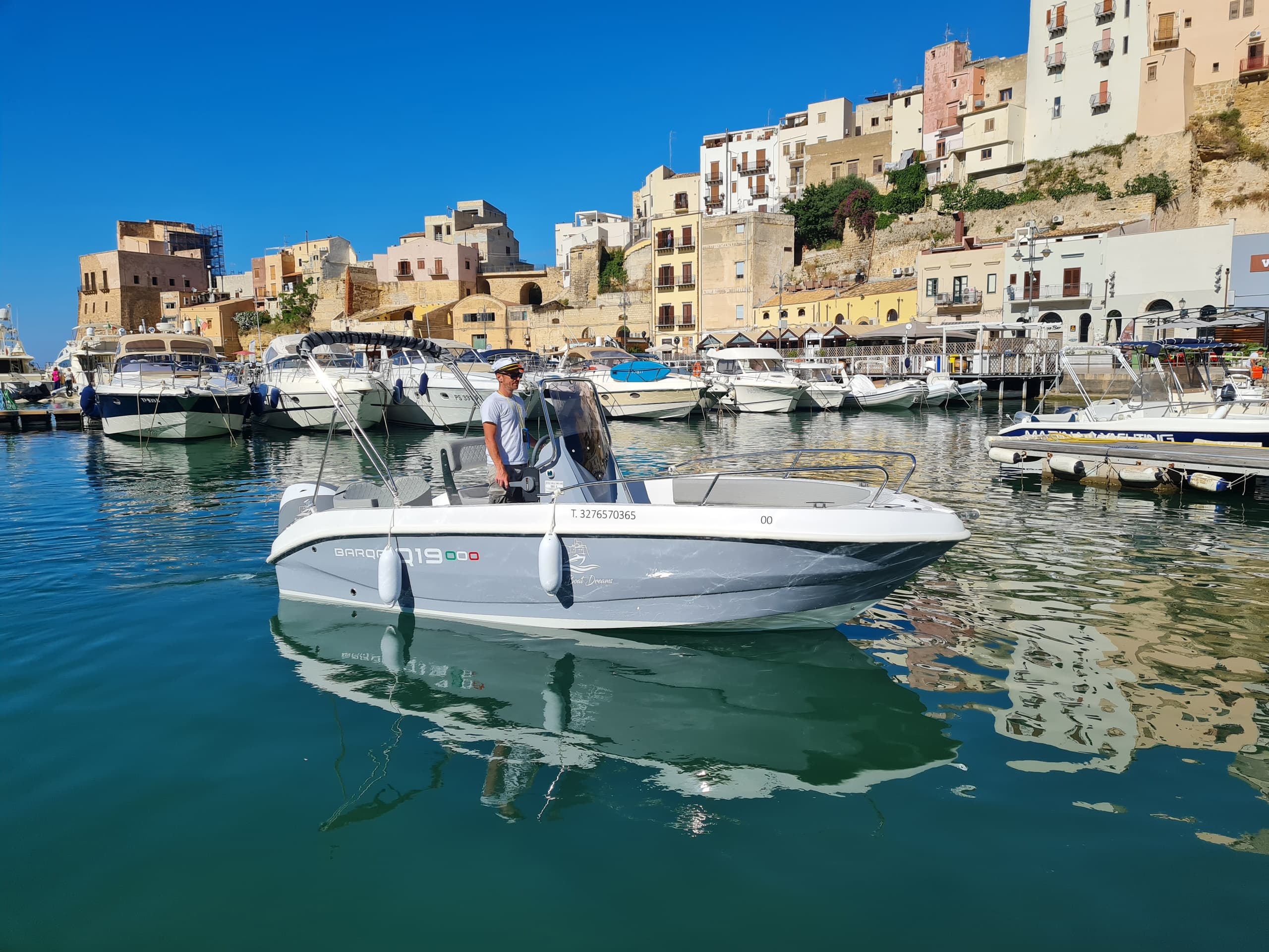 Boat tour in sunny Sicilian harbor with reflections and old town