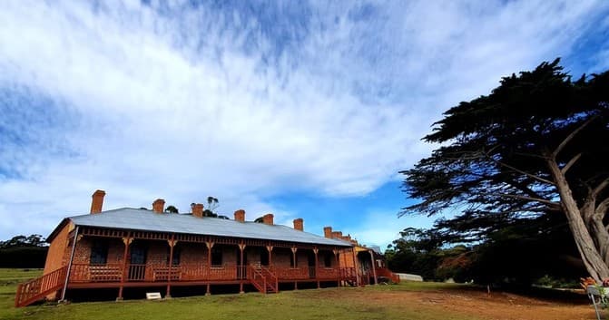 Historic rural homestead on grassy grounds, ideal for site touring