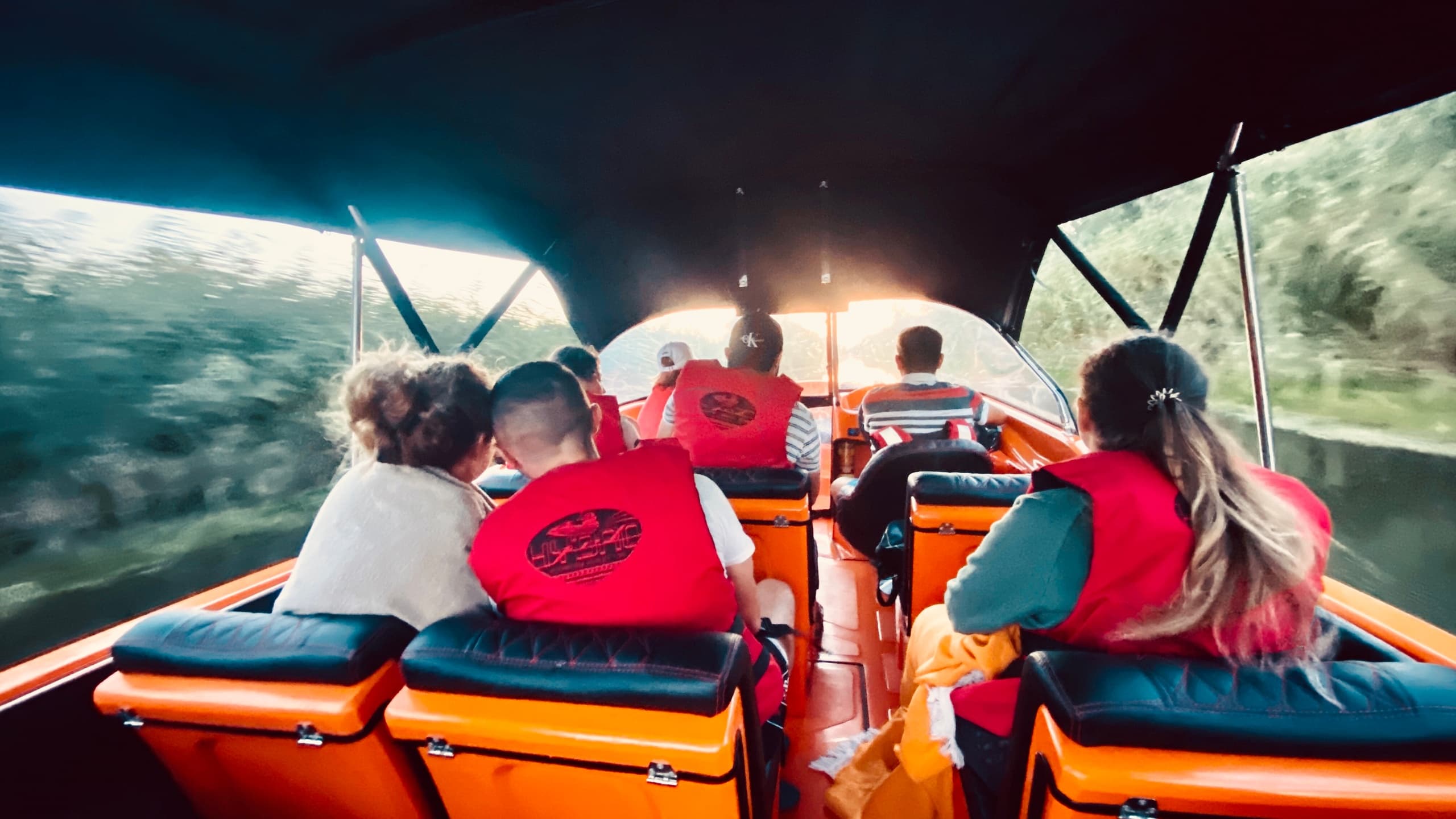 Passengers in lifejackets on open speedboat through river gorge