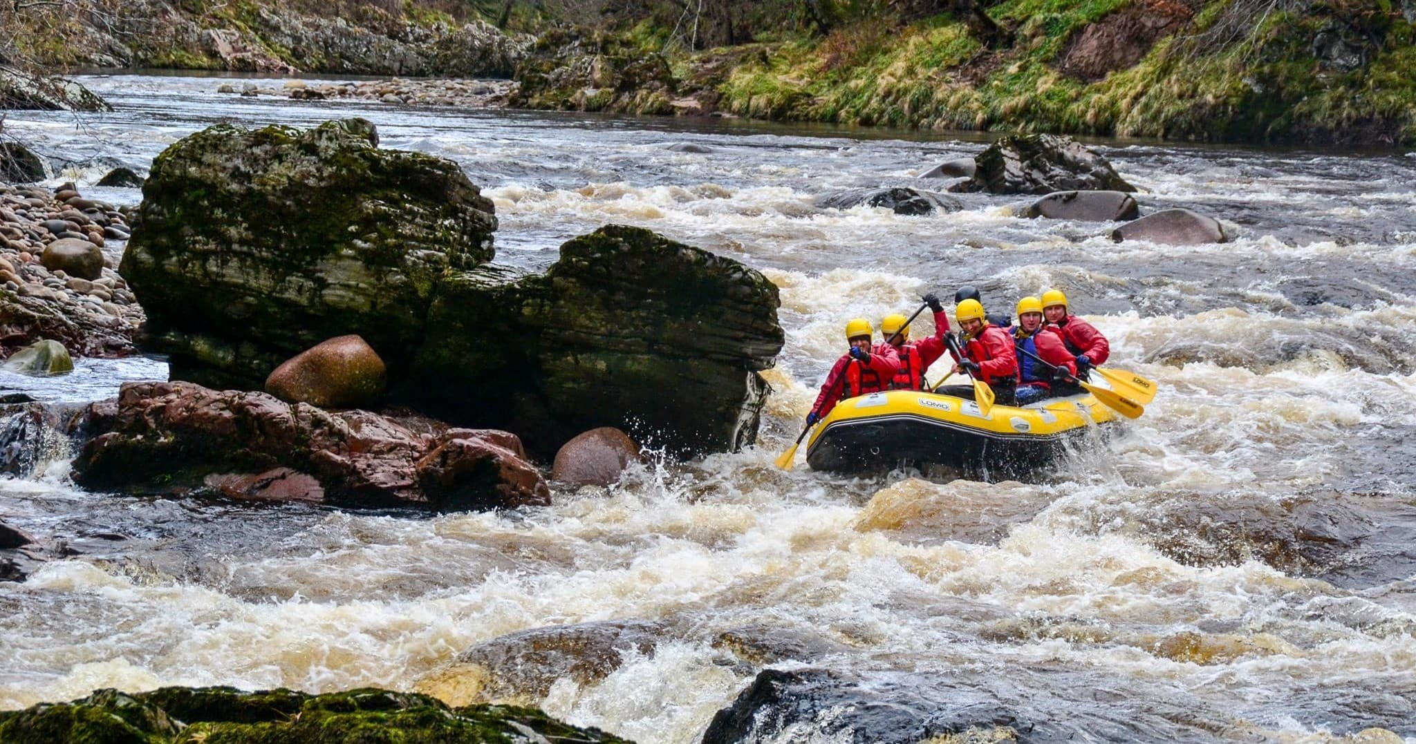 Whitewater rafters navigating rocky river rapids, adrenaline