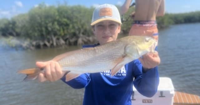 Angler holding redfish on boat during Florida inshore fishing trip