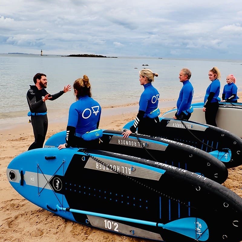 Sea kayak and paddleboard participants prepping on sandy beach