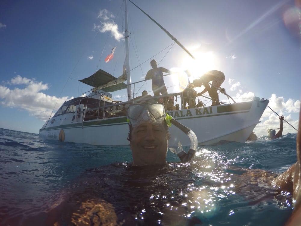 Snorkelers near catamaran boat in tropical ocean tour excursion