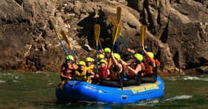 Whitewater rafters paddling near steep rock walls on river