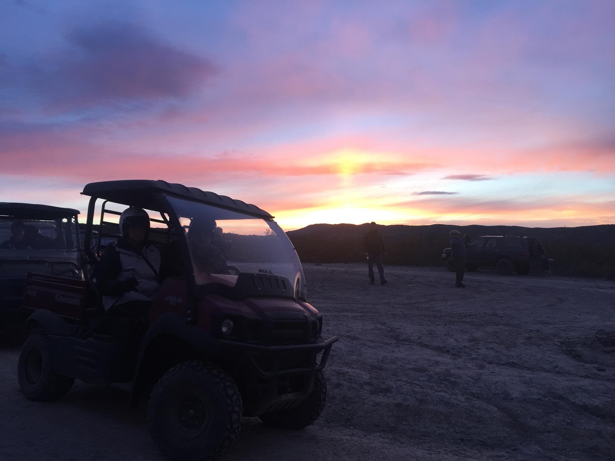 UTV silhouetted at colorful sunset over desert landscape