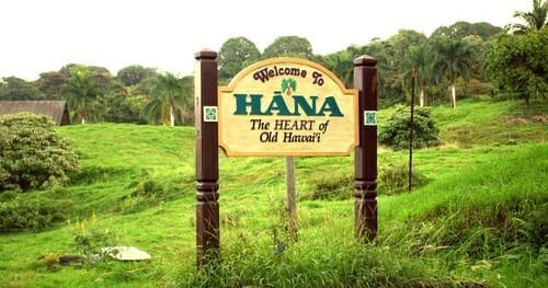 Welcome sign to Hana in lush green fields, island entrance