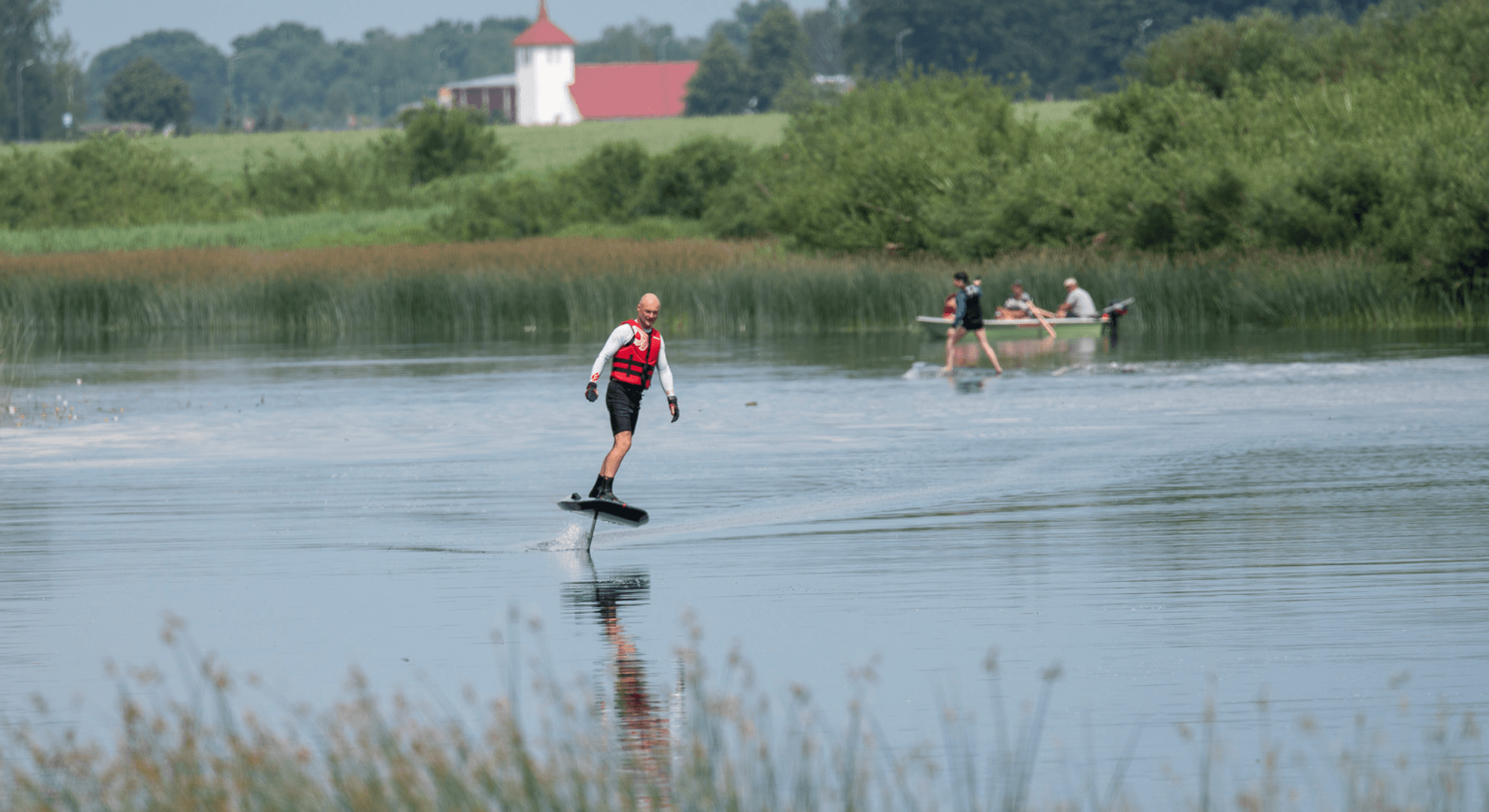 E-foil rider gliding across calm lake with distant shoreline