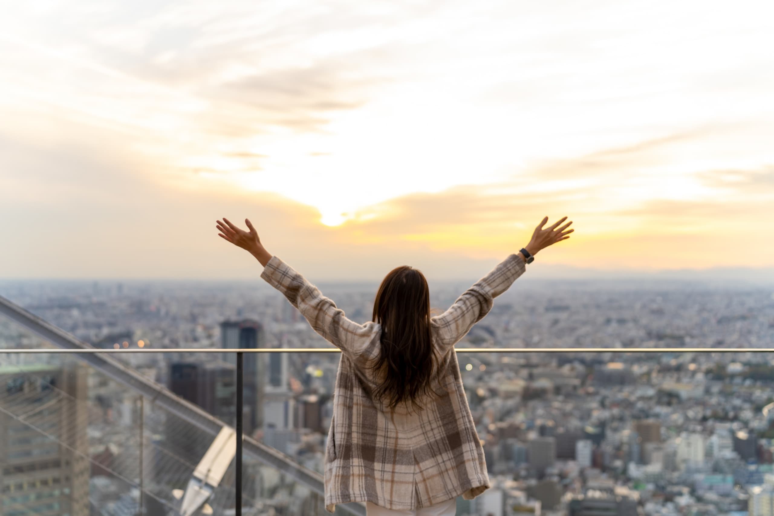 Traveler overlooking Tokyo skyline at sunset from rooftop view