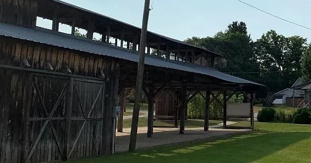 Wooden pavilion or picnic shelter in green park setting on lawn