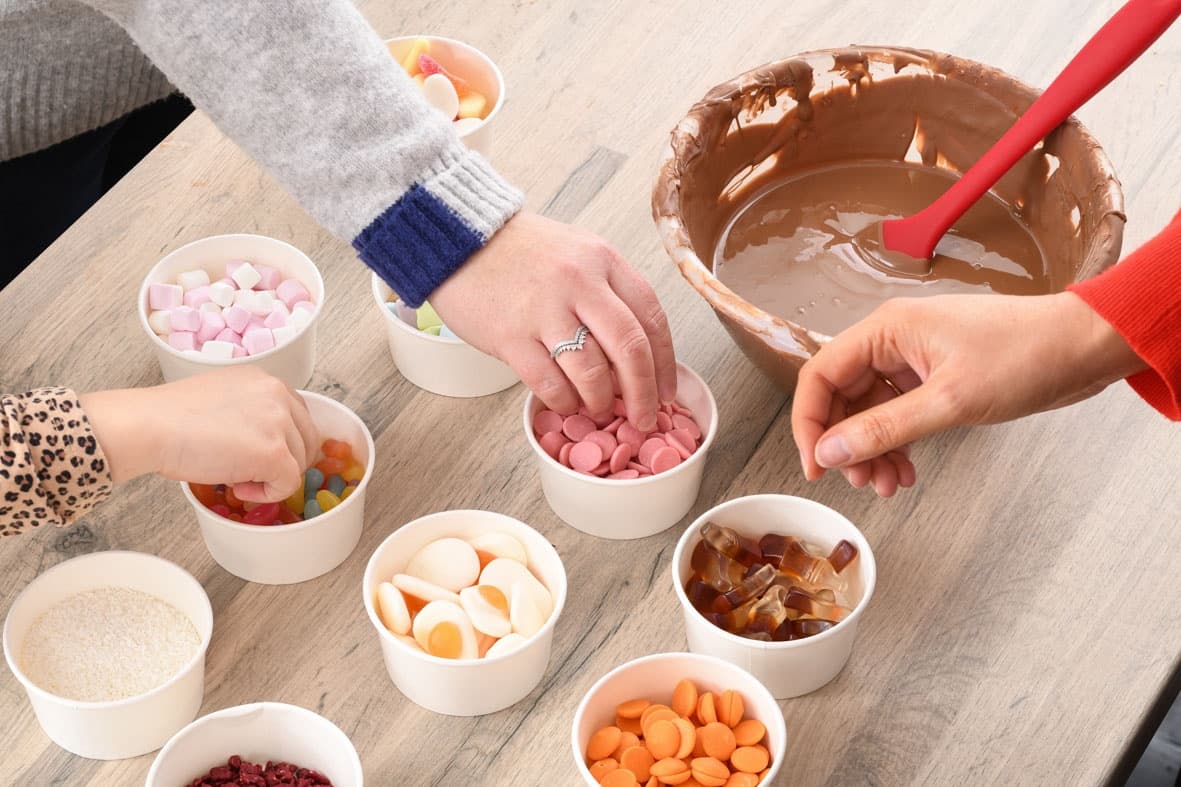 Hands decorating chocolates with candy toppings at workshop