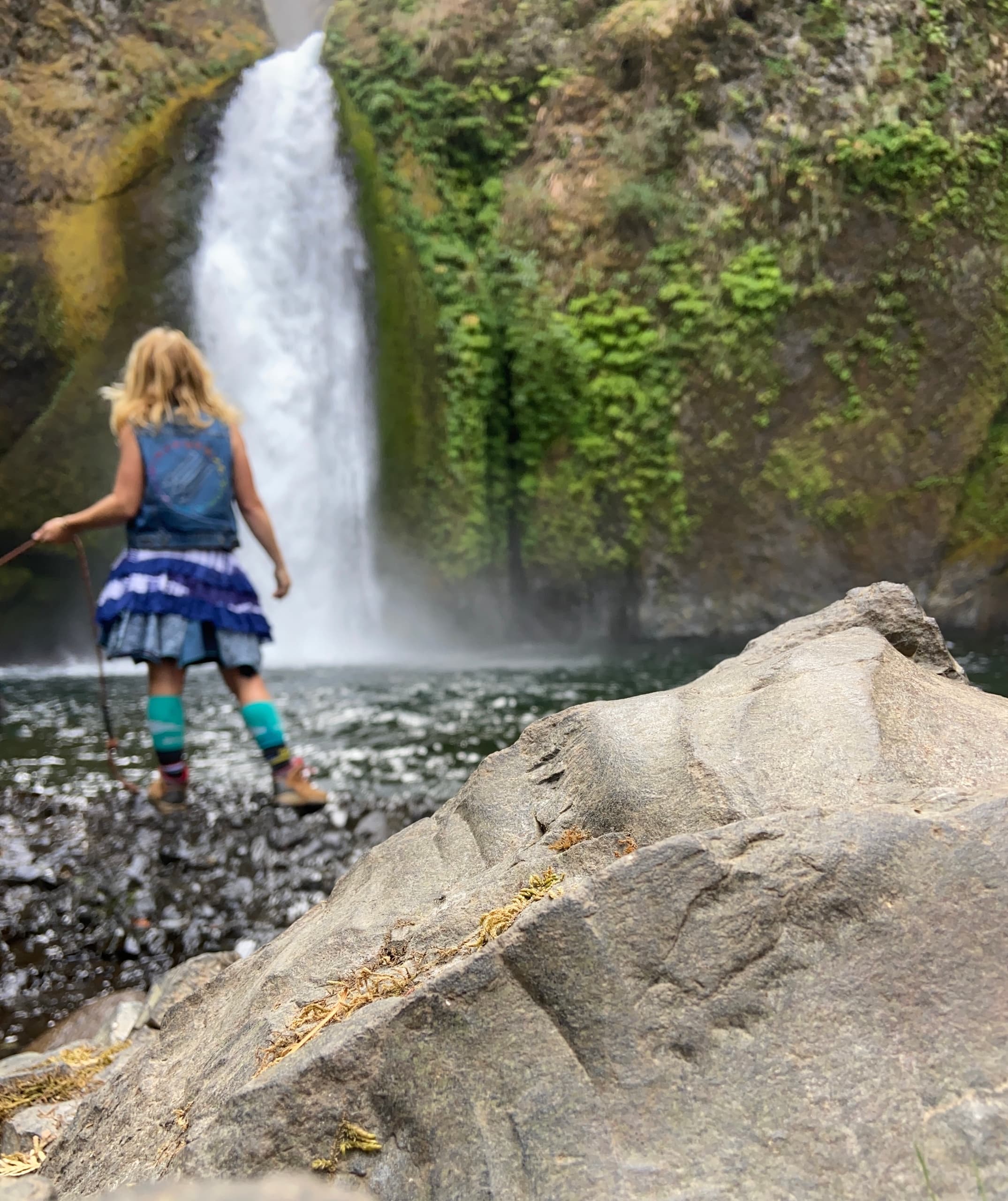 Child exploring waterfall pool at lush Multnomah Falls trail