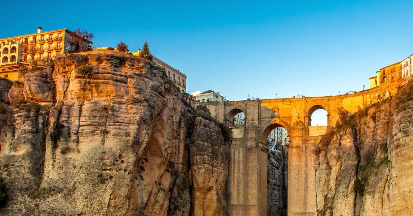 Golden-hour view of historic city bridge over river in Spain