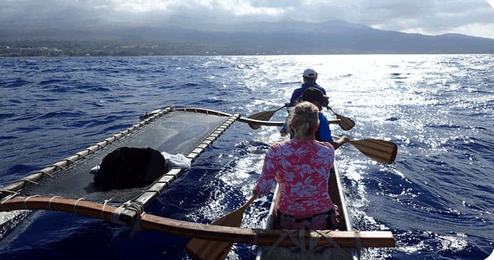 Traditional outrigger canoe paddling on open Pacific near Maui