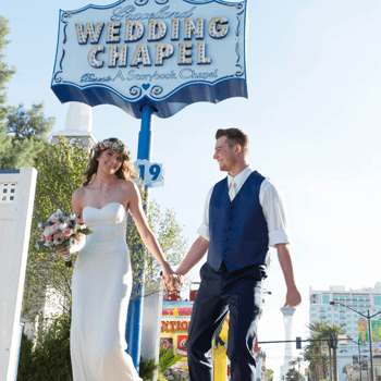 Bride and groom walking past classic Wedding Chapel sign outdoors