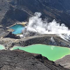 Hikers overlooking emerald crater lakes on Tongariro alpine trail