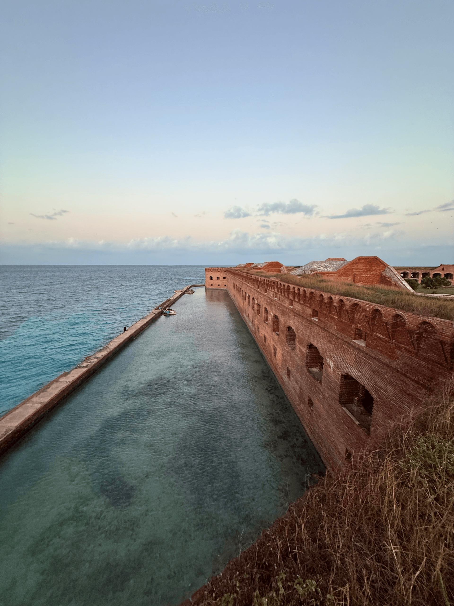 Historic fort pier leading into turquoise sea, coastal excursion