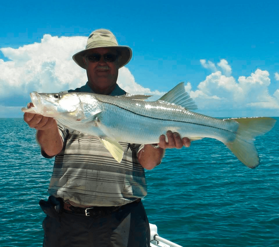 Fisherman displaying large snook over turquoise open ocean