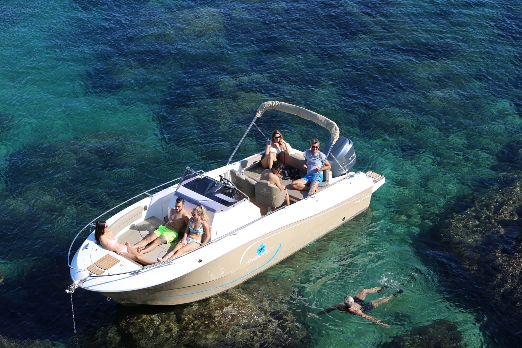 Aerial view of boat over clear turquoise water with snorkeler