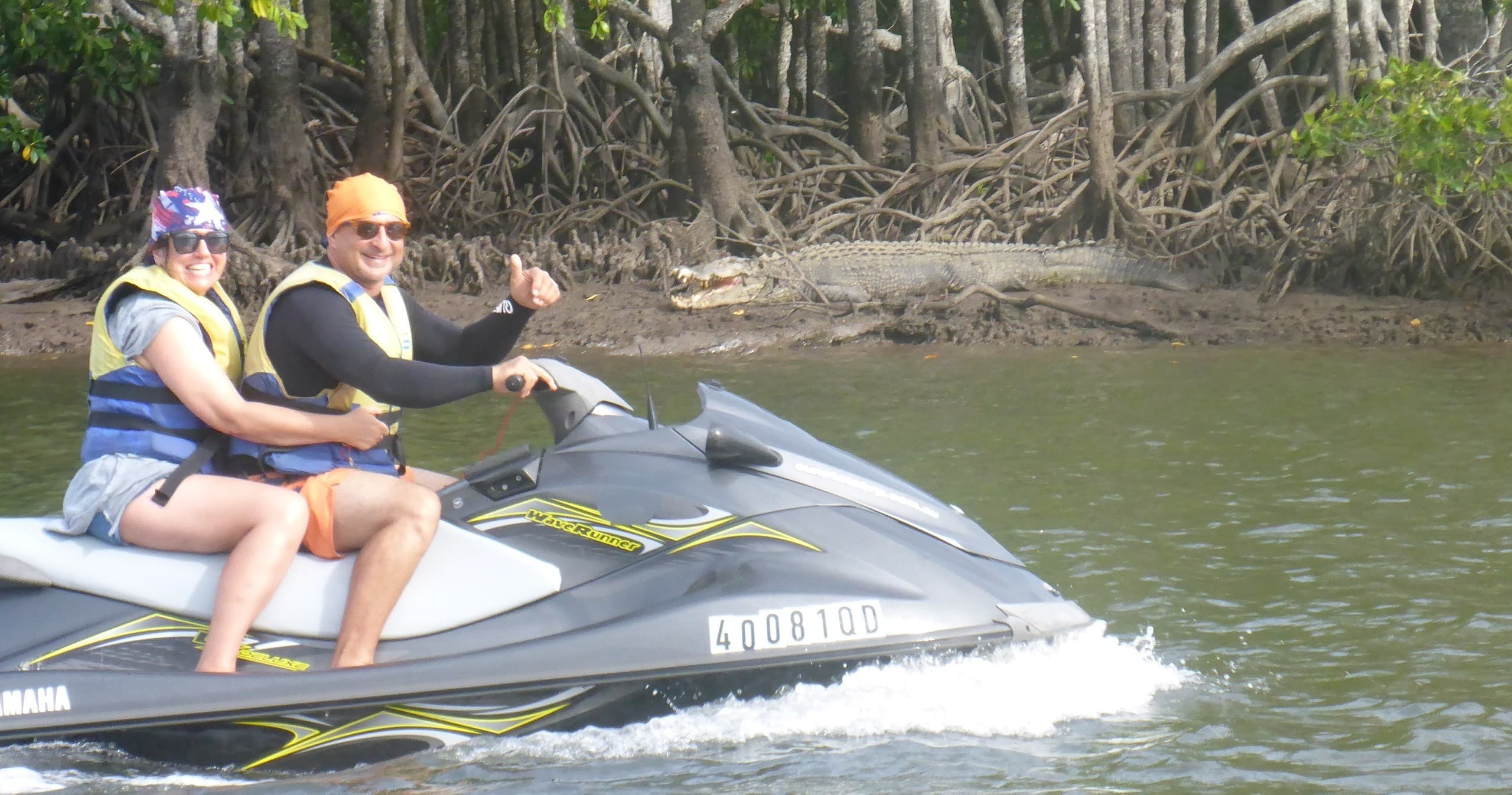 Couple on jet ski riding near mangrove-lined shoreline in calm bay