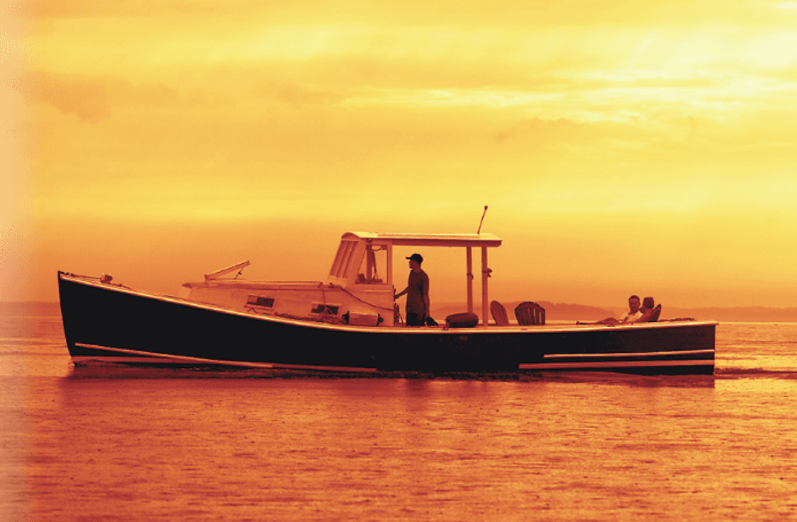 Fishing boat silhouetted at golden sunset on coastal waters
