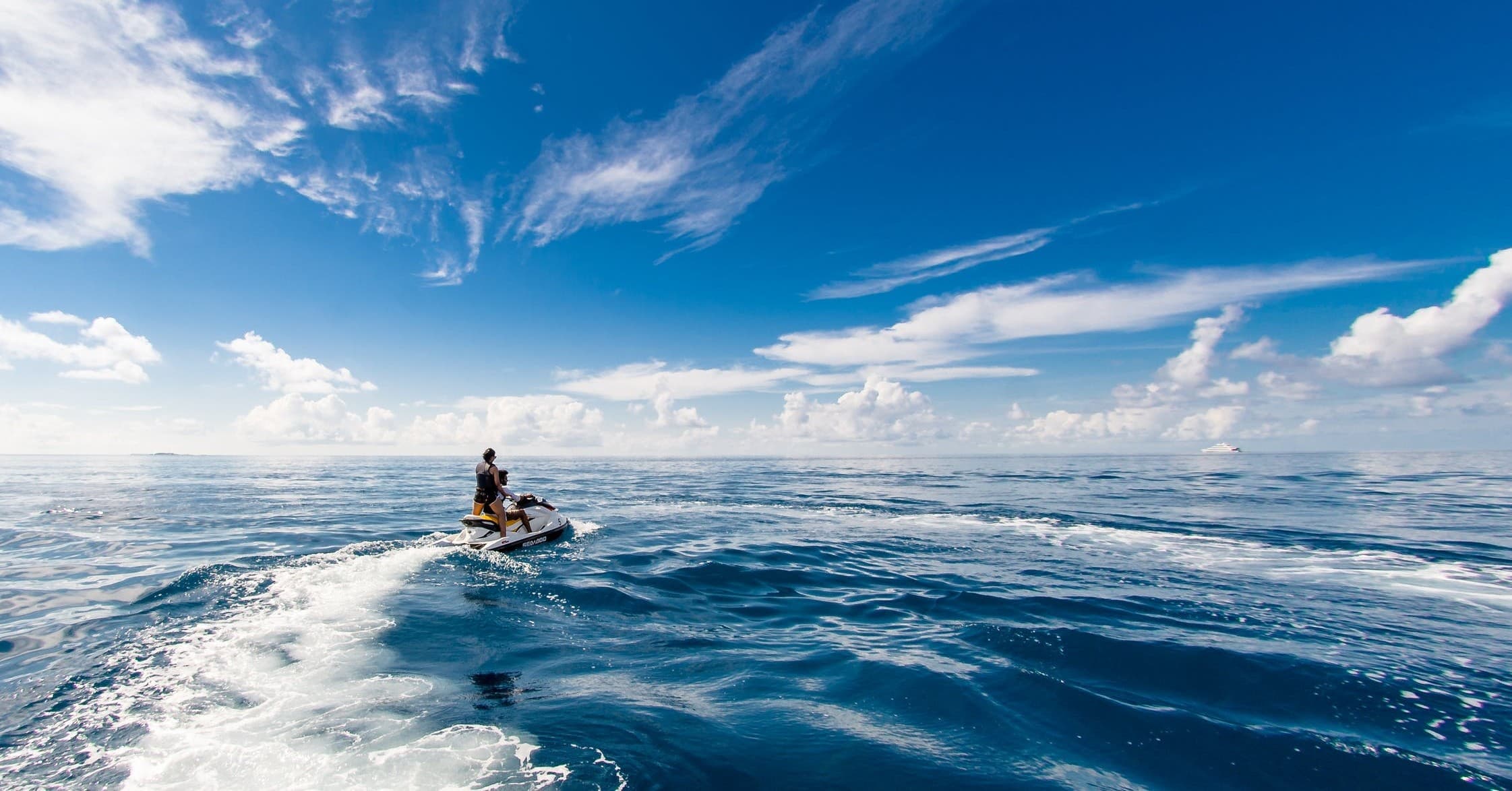Jet skier riding across open ocean under blue sky
