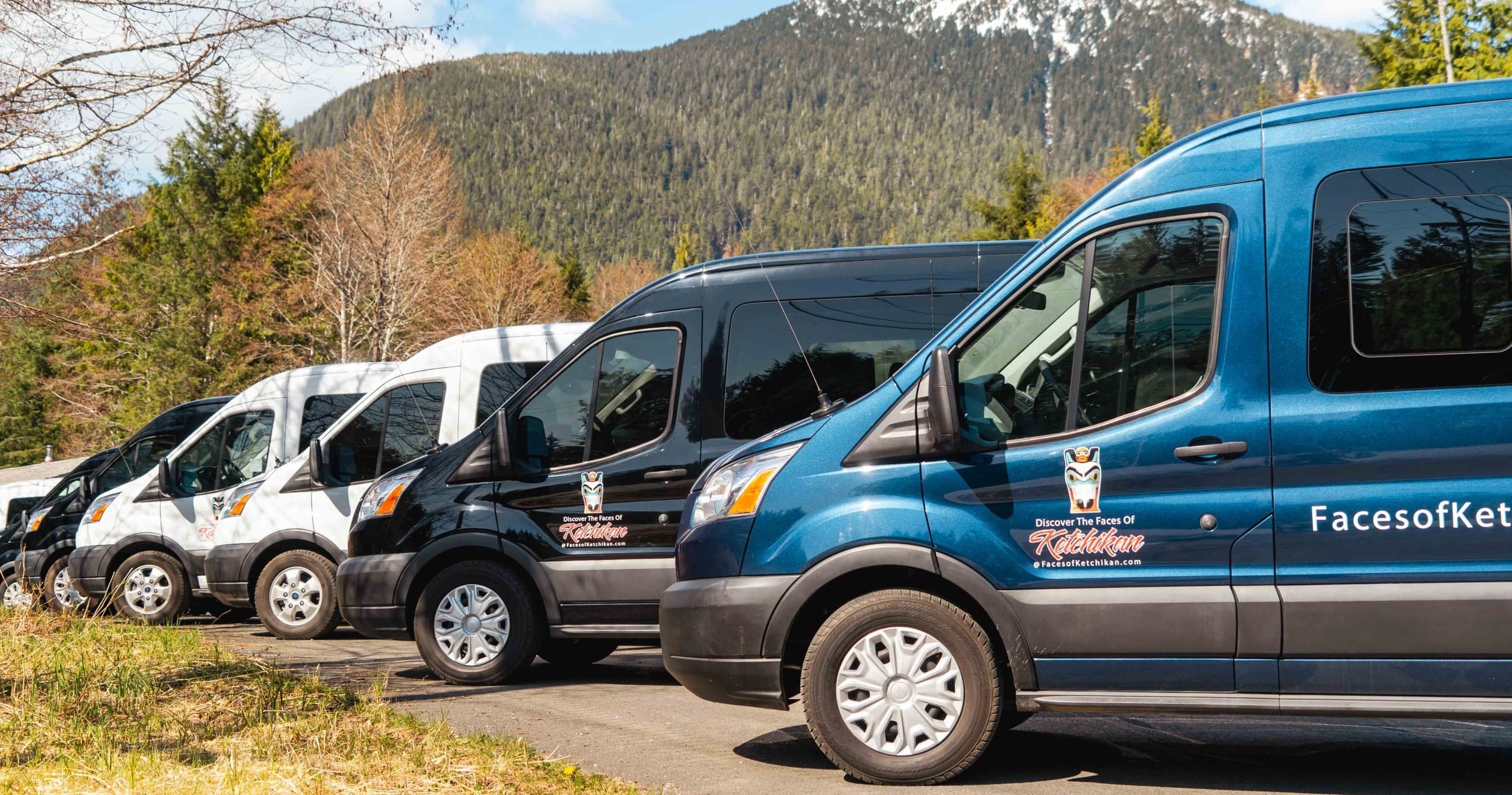 Tour vans parked with mountain backdrop near Ketchikan harbor