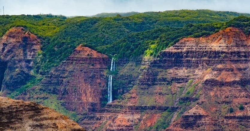 Canyon waterfall vista on Kauai rugged cliffs, scenic overlook