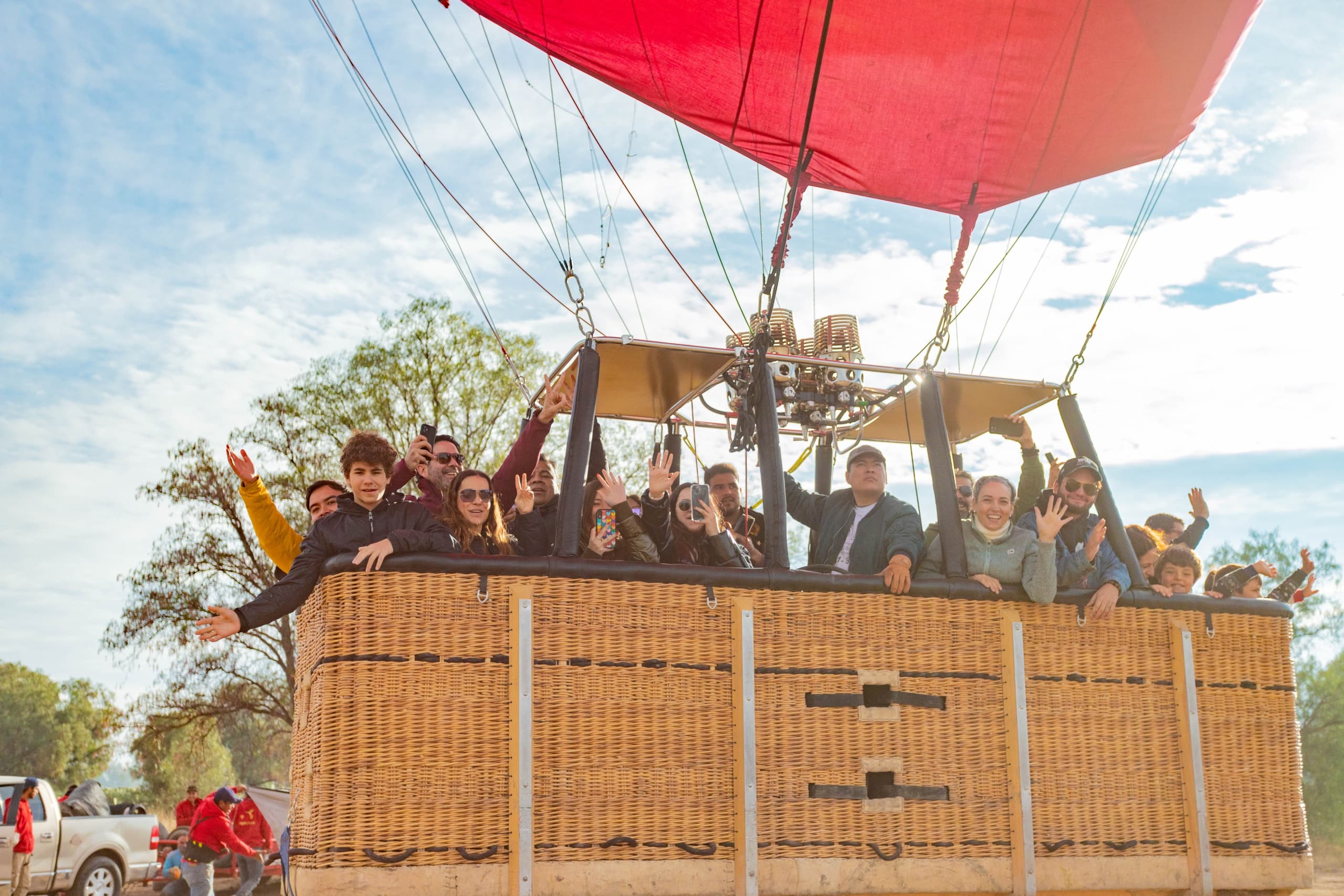 Passengers waving from a wicker hot air balloon basket