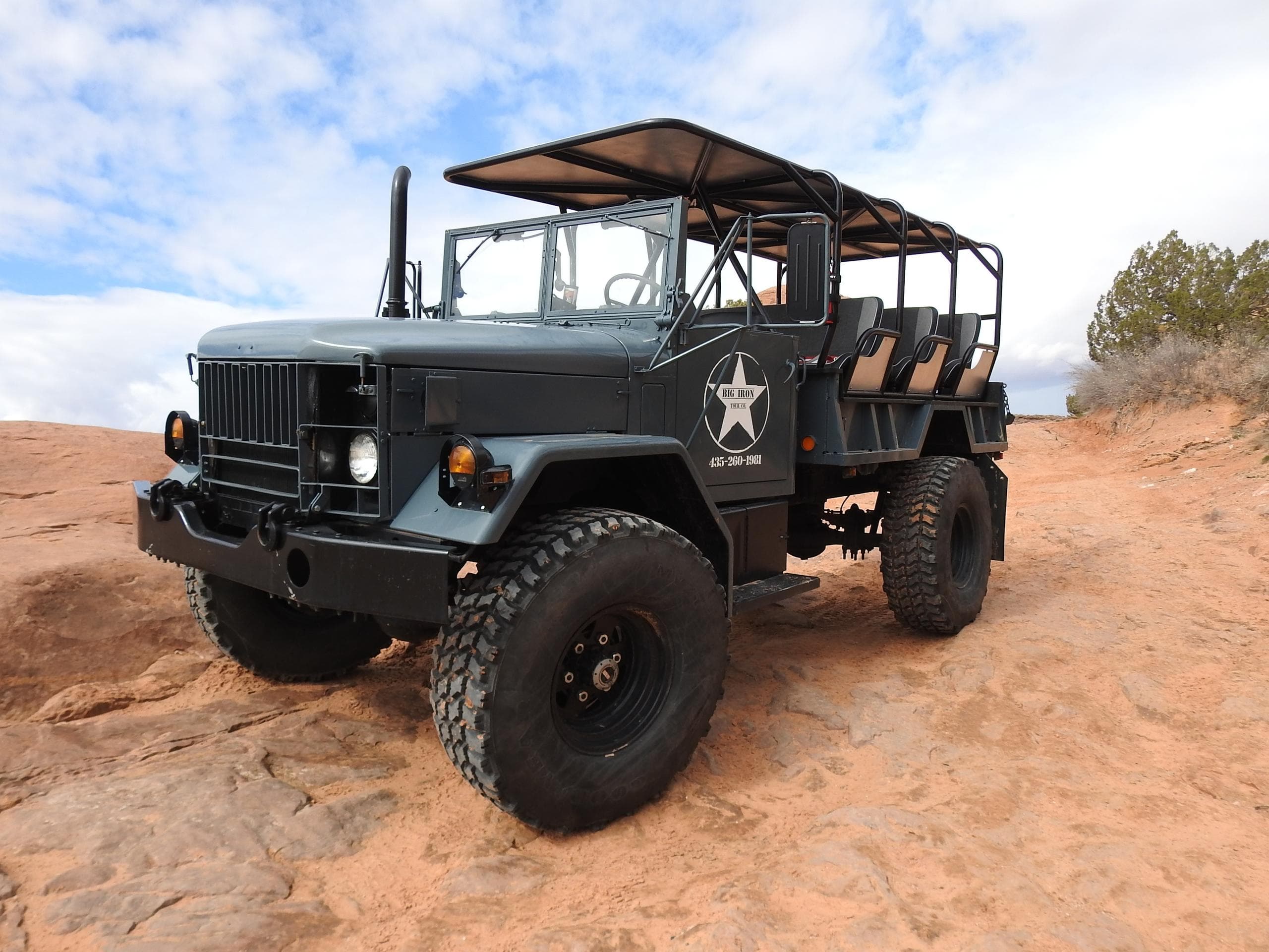 Open-top six-wheel expedition truck parked on sandstone trail
