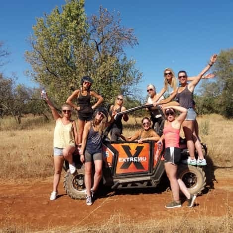 Group posing on orange off-road buggy in dry savanna terrain