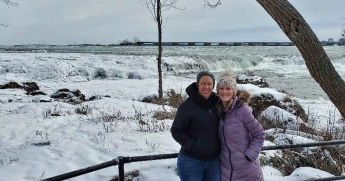 Couple viewing icy Niagara Falls winter shoreline on tour