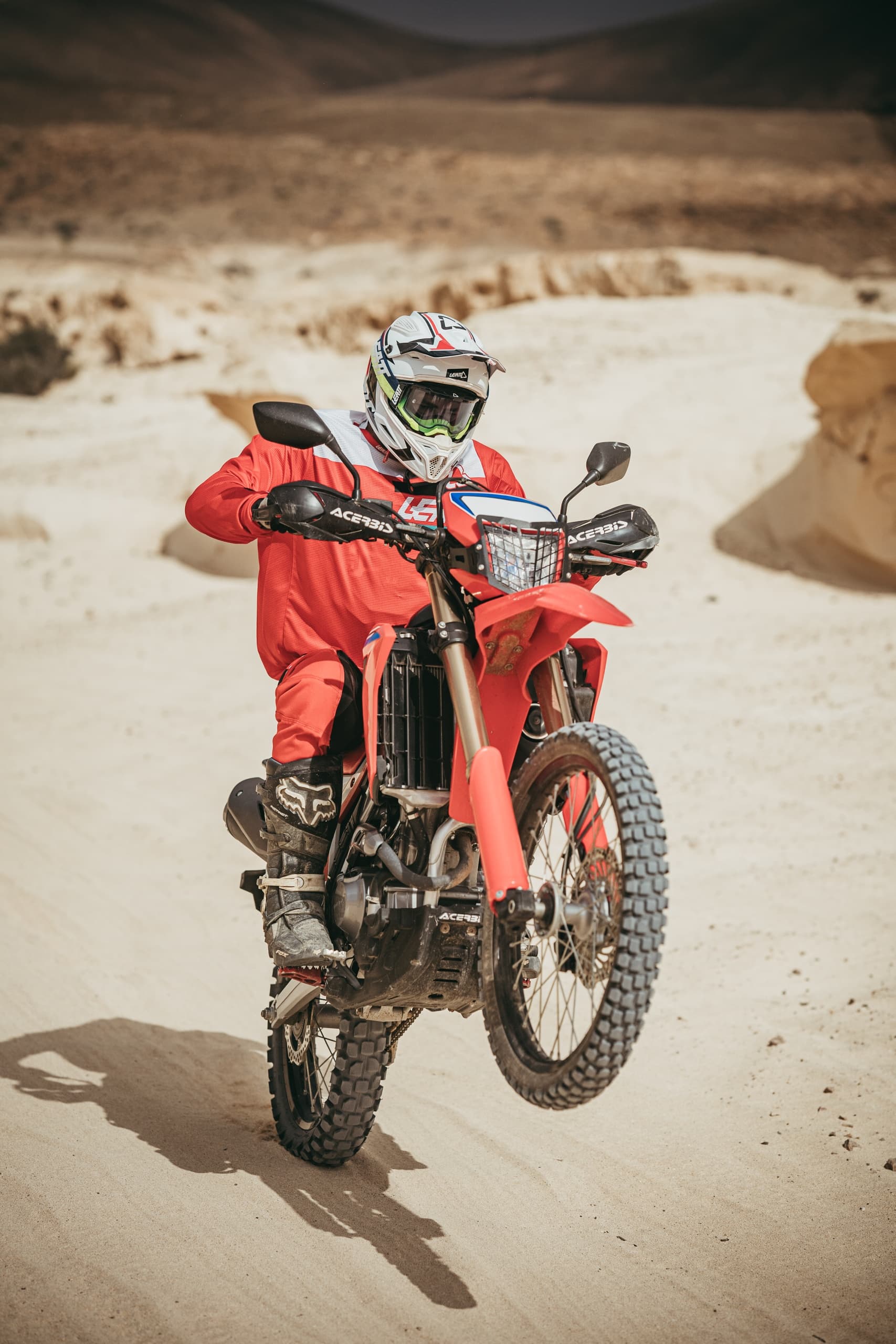Motorcyclist doing wheelie on sandy desert trail in Fuerteventura