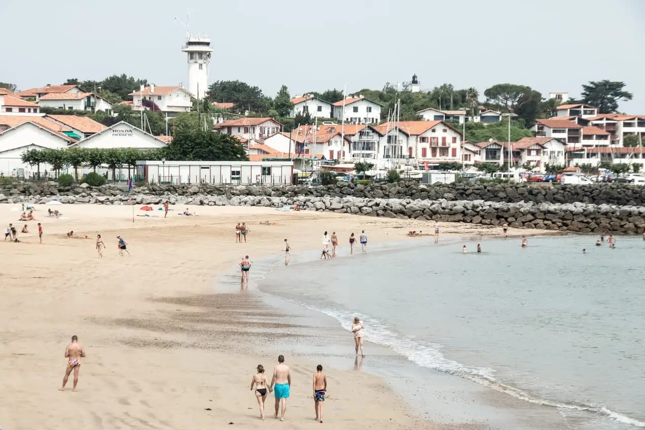 Sandy beach and seaside town with swimmers and coastal hills