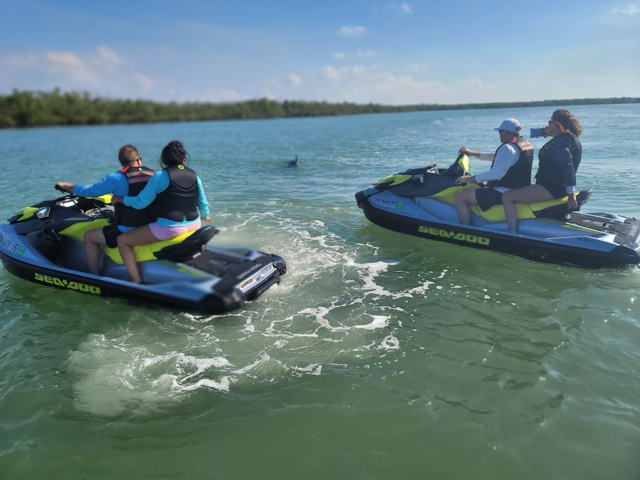 Jet ski riders cruising coastal turquoise waters near islands