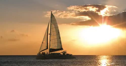 Sailboat cruising at sunset over coastal ocean waters, scenic horizon