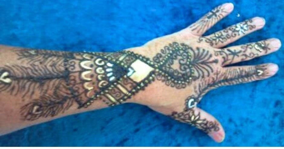 Decorative henna hand art on bright blue fabric, close-up