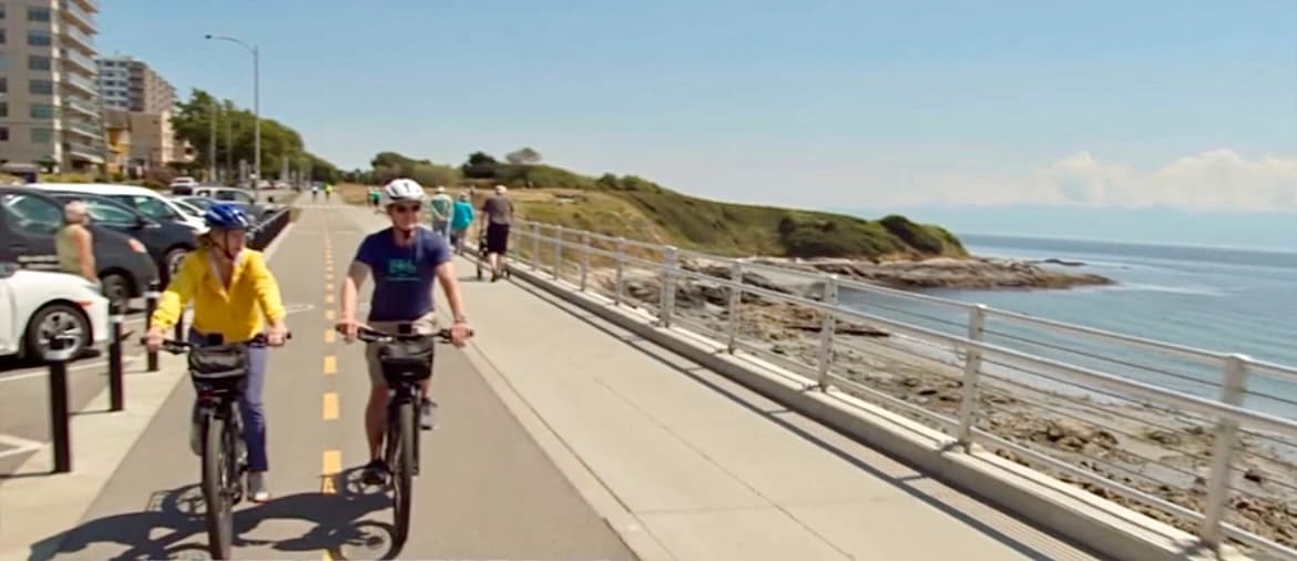 Cyclists riding along sunny seaside promenade with ocean views