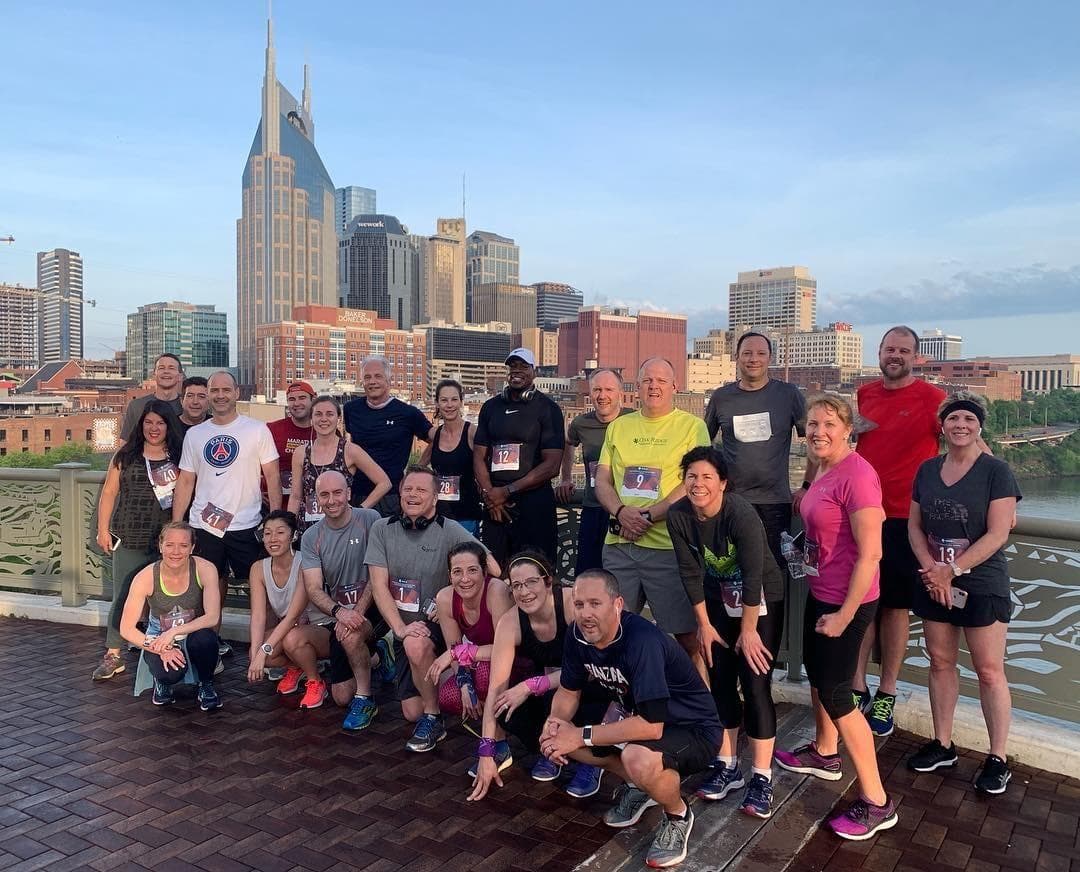 Group of runners posing after run on Nashville riverfront skyline