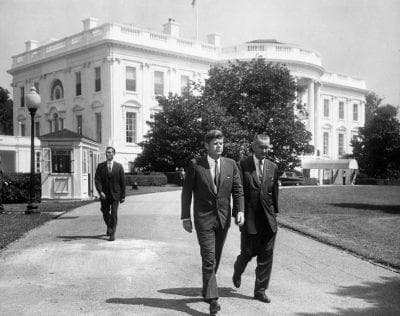 Men walking on White House grounds along tree-lined driveway