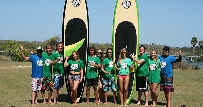Group lesson with stand-up paddleboards on grassy Byron Bay shore