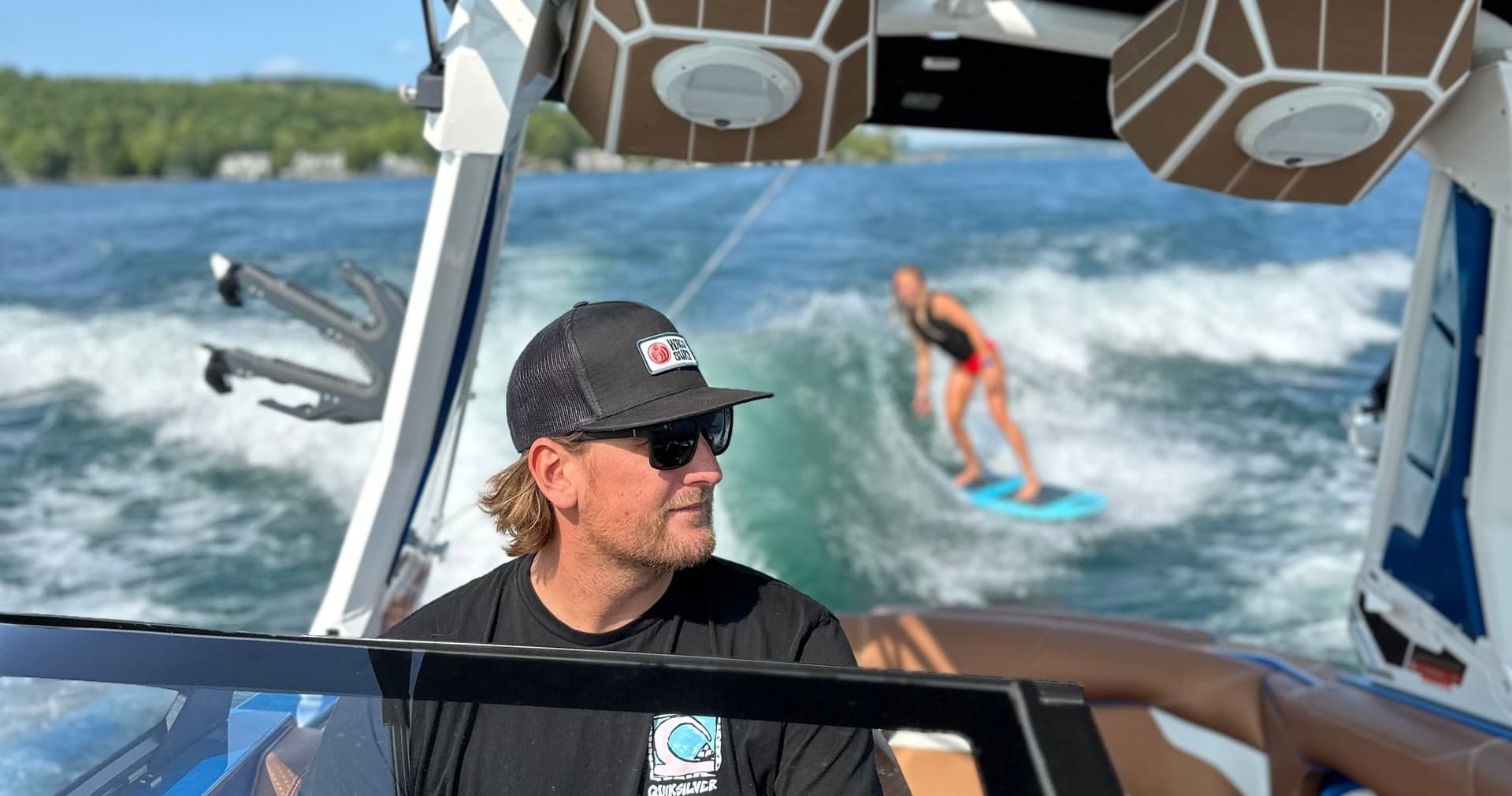Boat captain steering while wakesurfer rides the wake