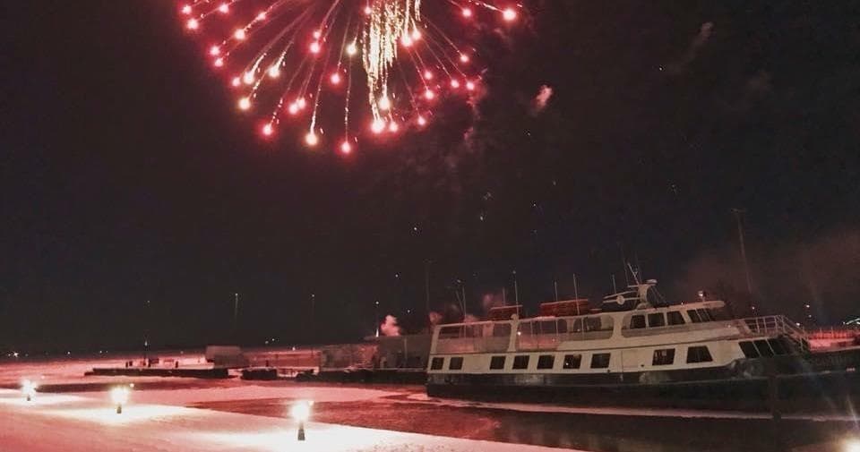 Fireworks over harbor with docked cruise boats at night