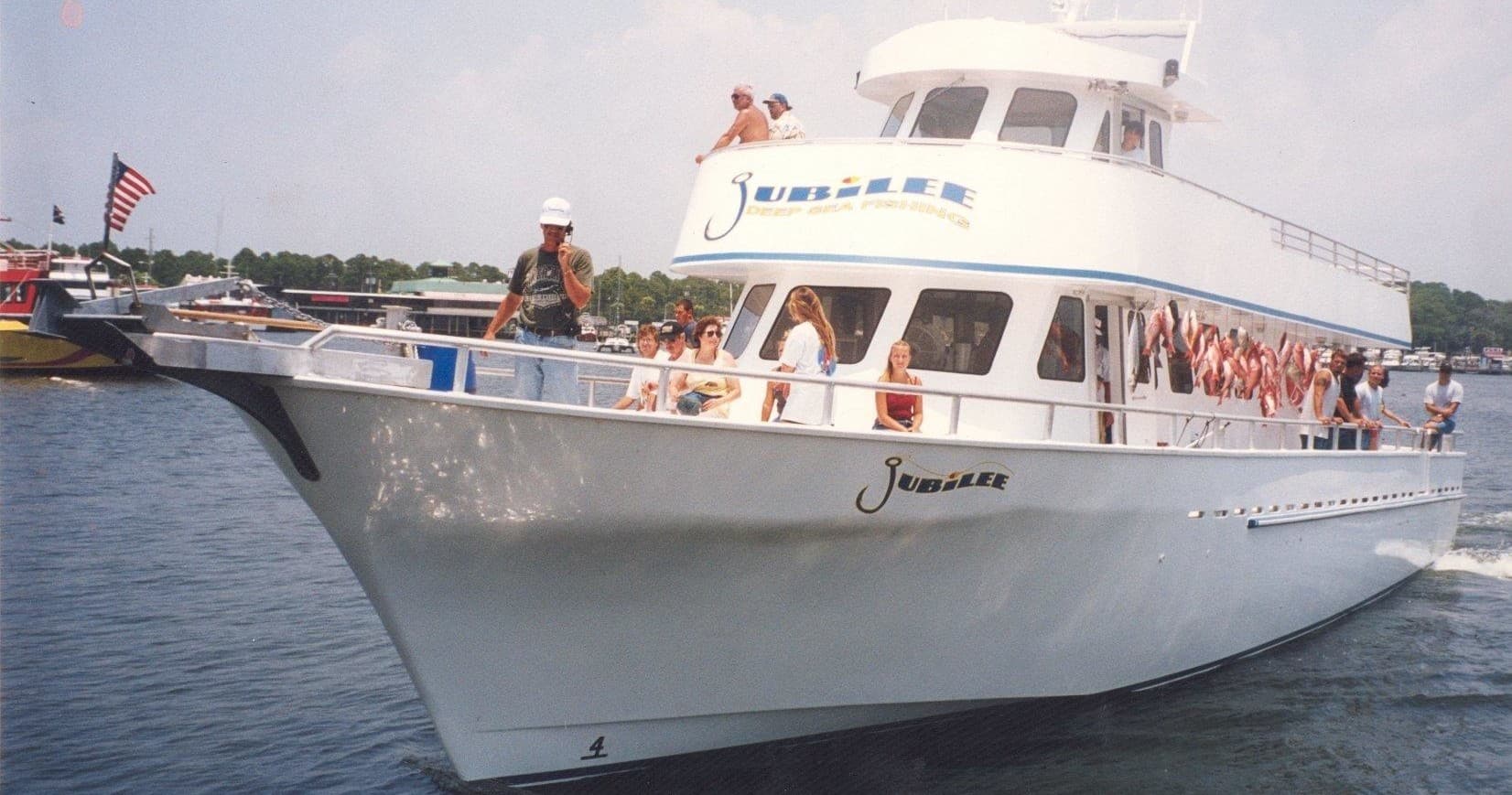 Large white charter fishing boat cruising coastal waters