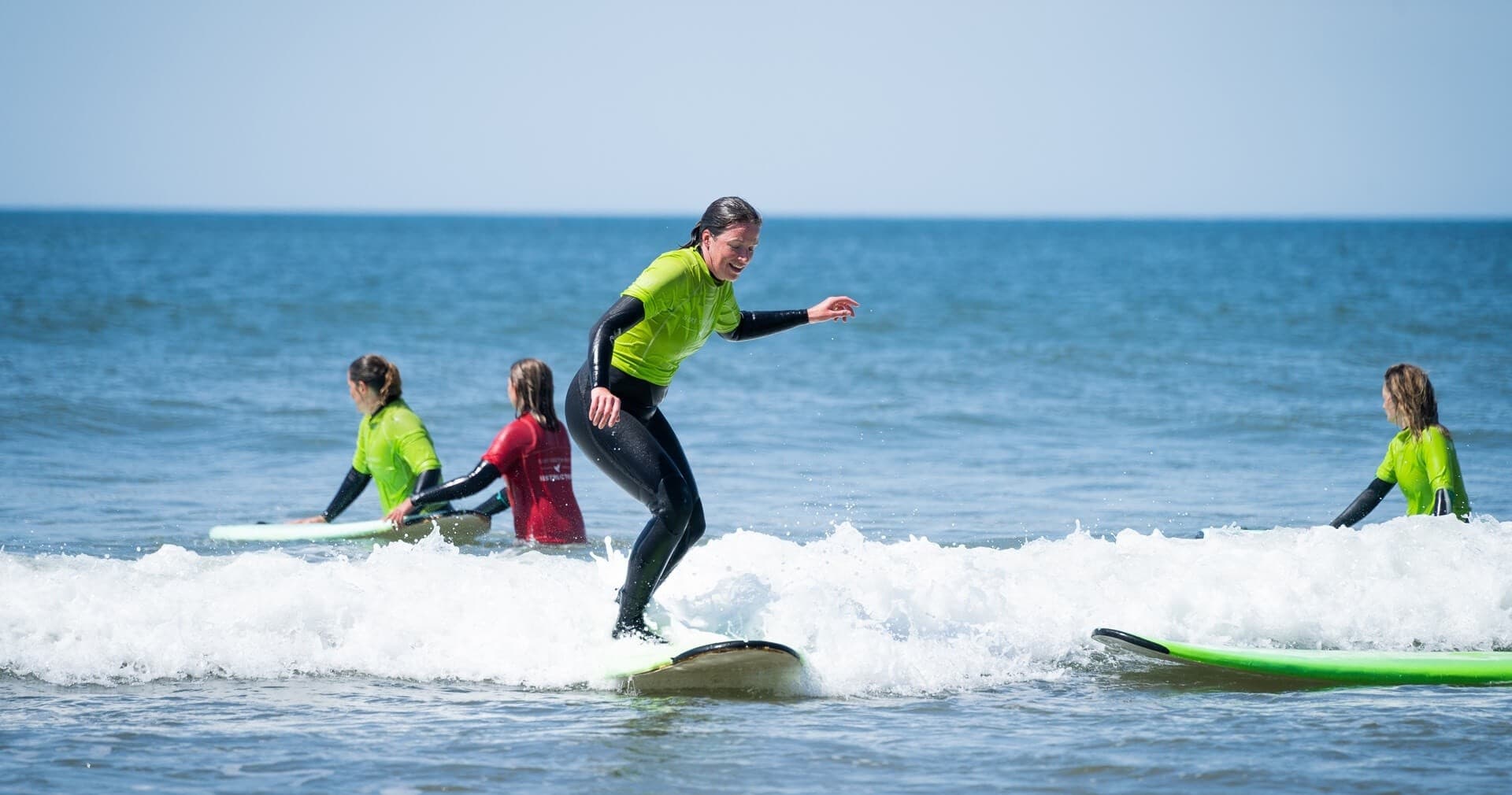 Surfers riding small ocean waves on a sunny Cornwall beach