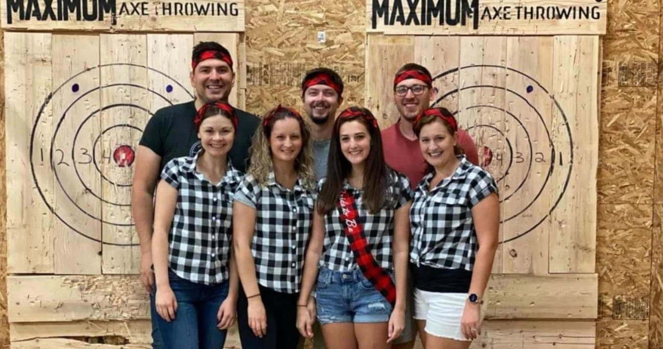 Group of friends celebrating at indoor axe throwing lanes with wooden targets