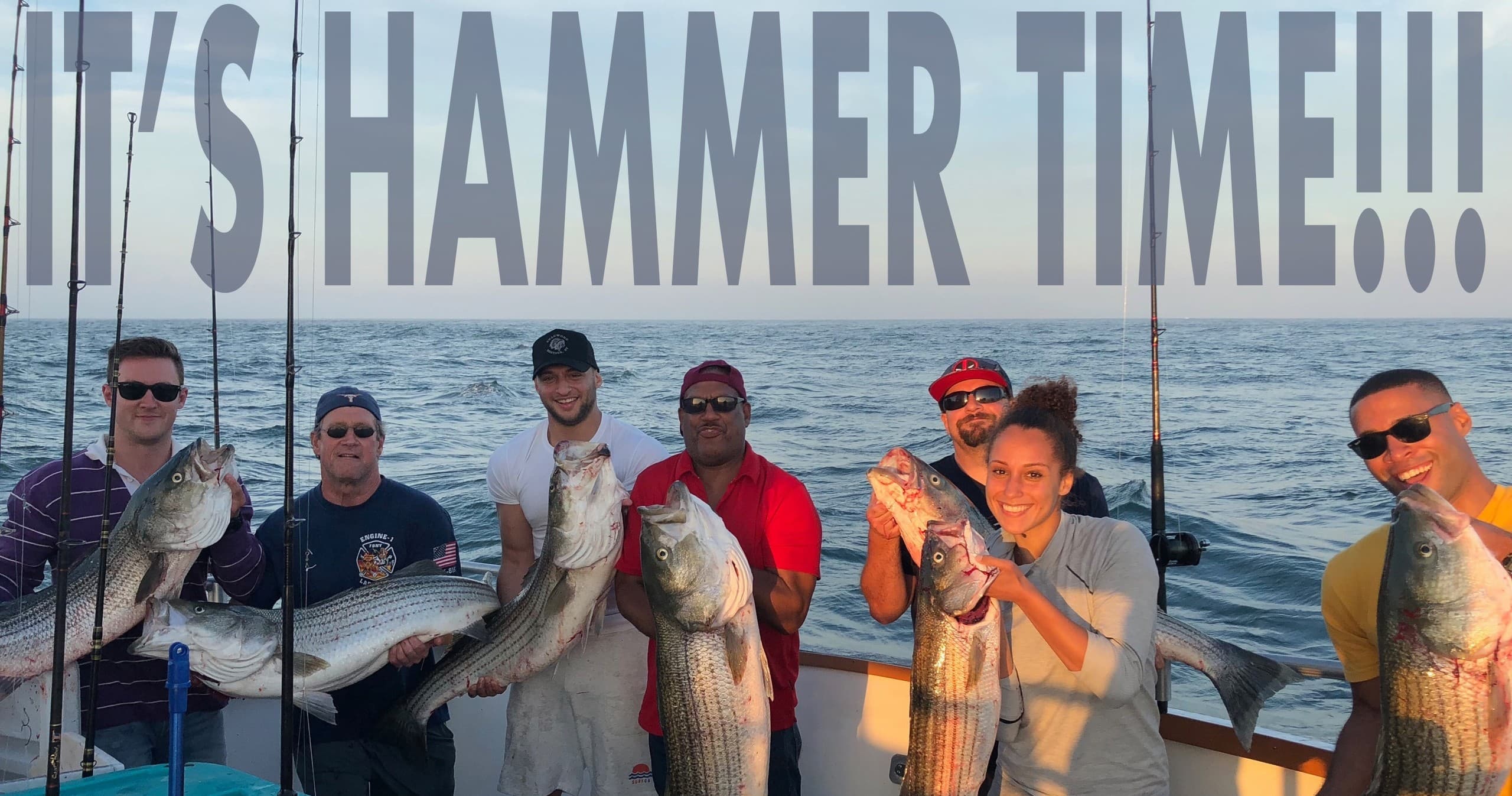 Group of anglers holding striped bass on charter boat, trophy catch